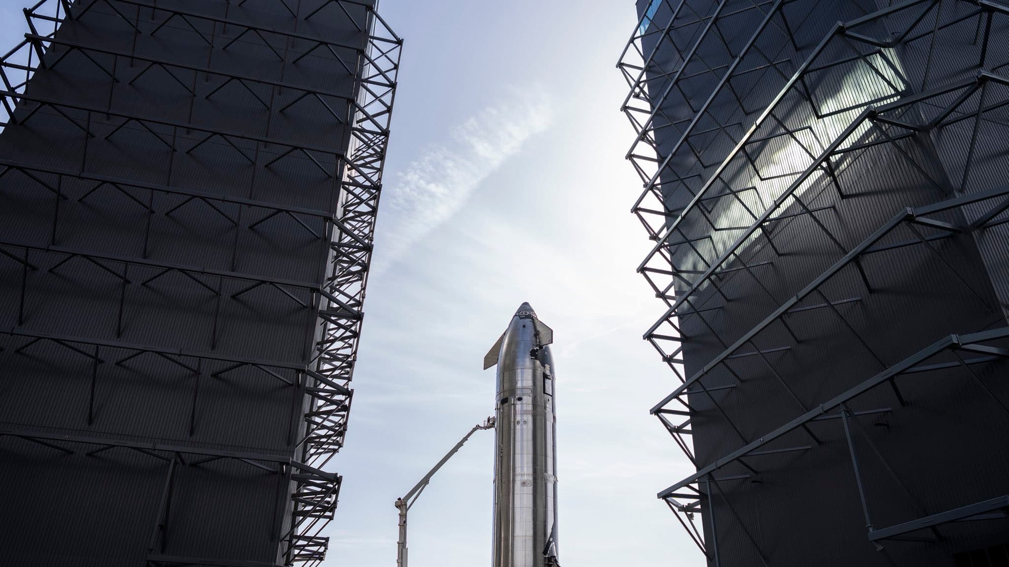 A Starship stands between two launch towers at Starbase, Texas.